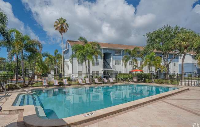 a large swimming pool in front of a building with palm trees