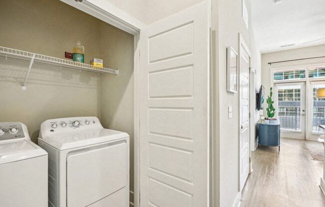 a laundry room with a washer and dryer and a white door at Link Apartments Innovation Quarter, Winston Salem