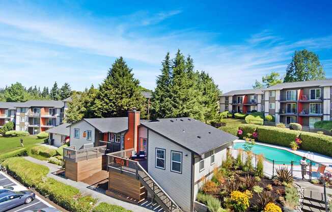 A small house with a grey roof is surrounded by a well-kept garden.