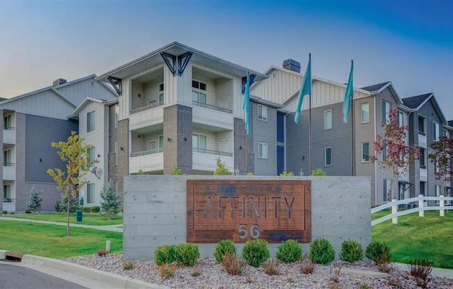 an apartment building with a sign in front of it at Affinity 56 Apartments in West Jordan, Utah