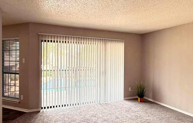 A room with a carpeted floor and a window with blinds.