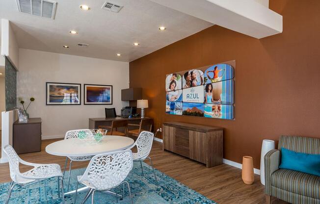 A living room with a white table and chairs, a blue rug, and a brown cabinet.