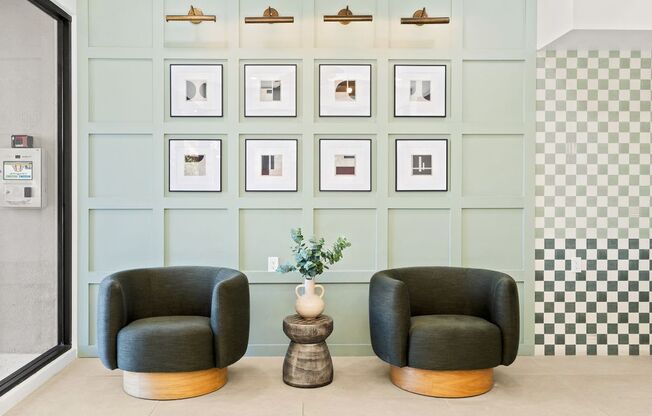 Two black chairs are in front of a wall with pictures on it.