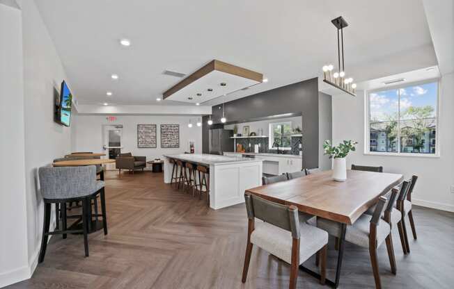 a dining area with a wooden table and chairs and a kitchen in the background