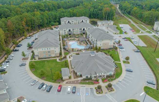 an aerial view of an apartment complex with parking lot and cars