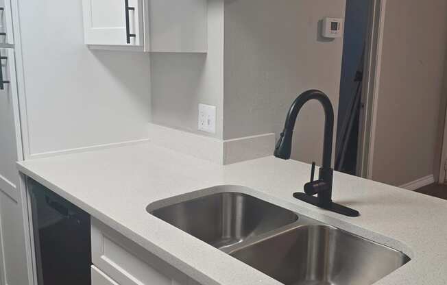 an empty kitchen with white cabinets and a sink