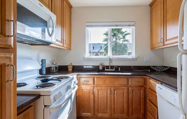 a kitchen with white appliances and wooden cabinets and a window