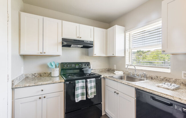Apartment kitchen with white cabinets and black appliances_Rolling Hills Apartments