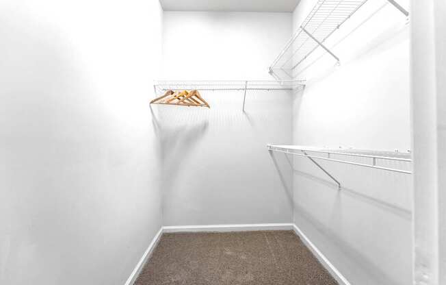 A white closet with a hanger and clothes hanging on it.