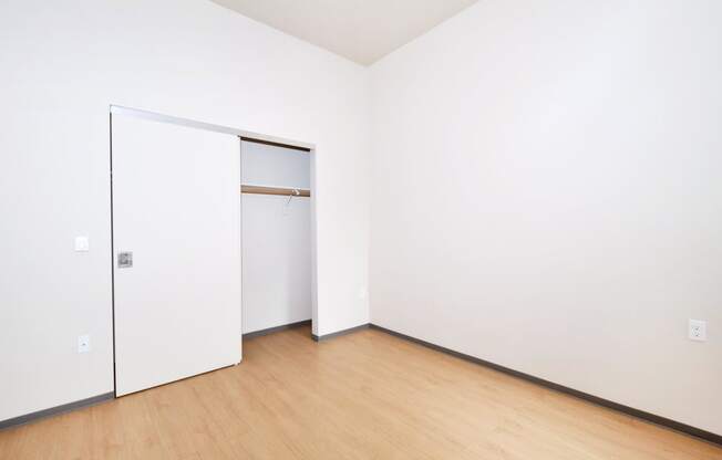 a bedroom with white walls and a wooden floor