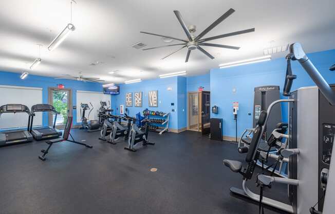 a gym with exercise equipment and a ceiling fan