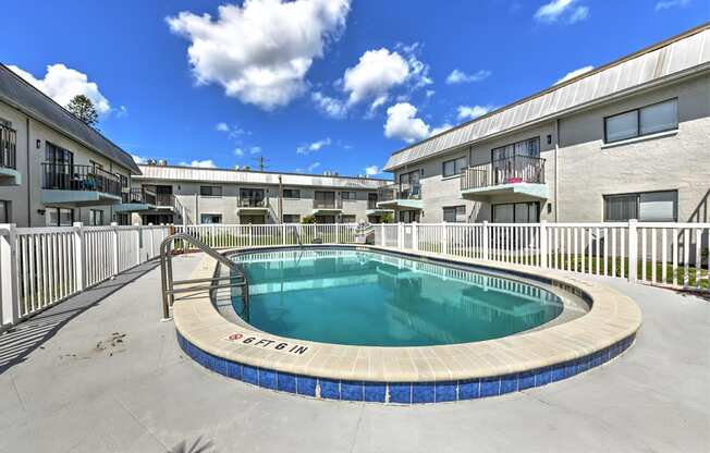 A swimming pool surrounded by a fence and buildings.