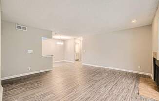 A spacious room with wood flooring and a doorway leading to another room.