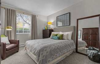 A bedroom with a large bed and a chair.