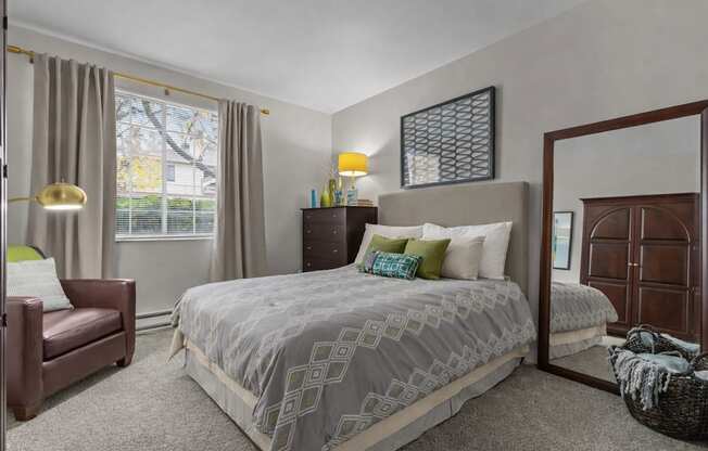A bedroom with a large bed and a chair.