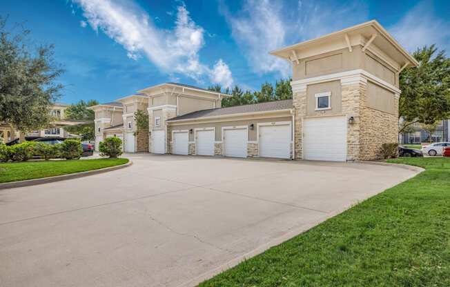 a driveway leading to a building with white garage doors