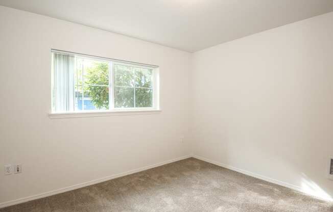 a bedroom with white walls and a window