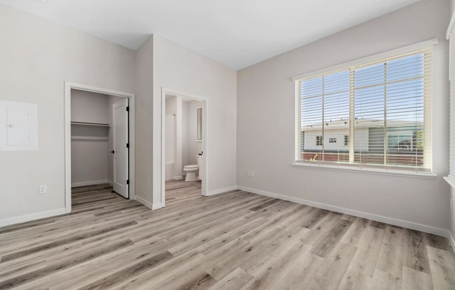 an empty room with a window and a door to a bathroom