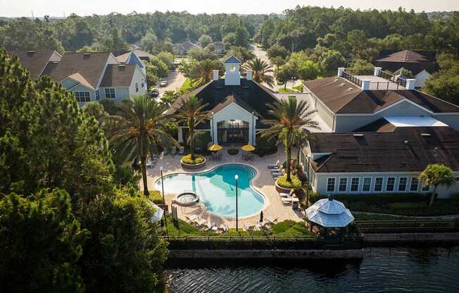 a aerial view of a swimming pool in front of a house and a lake