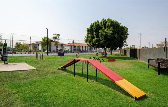 a park with a seesaw and benches on the grass