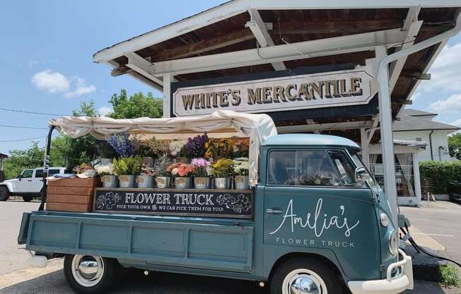 an old blue truck parked in front of a flower truck
