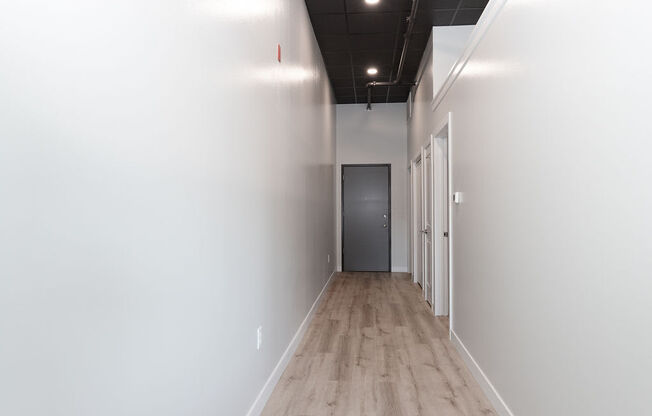 a hallway with white walls and wood floors and a door