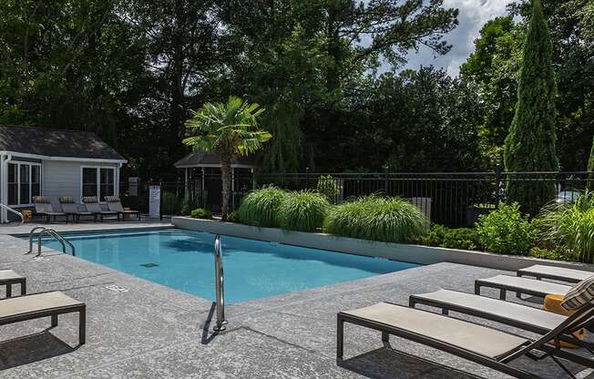 a swimming pool with lounge chairs and a gazebo in the background at Eclipse Apartments in Duluth