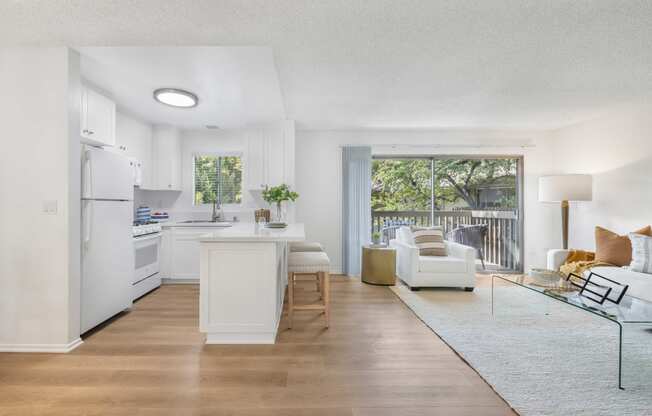 a living room and kitchen with a sliding glass door to a balcony