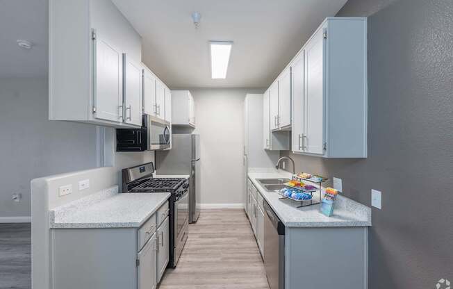 A kitchen with white cabinets and a grey countertop.
