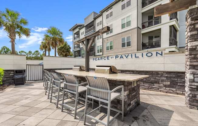 a patio with a bar and chairs in front of an apartment building