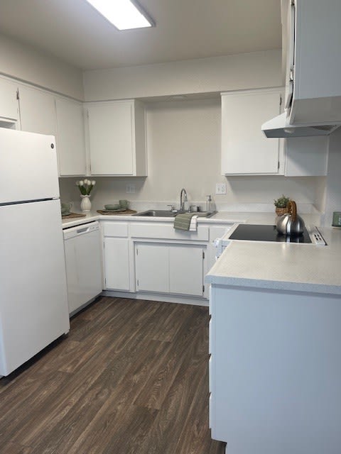 an empty kitchen with white cabinets and a refrigerator