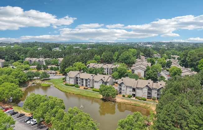 A bird's eye view of a residential area with houses, a lake, and a parking lot.