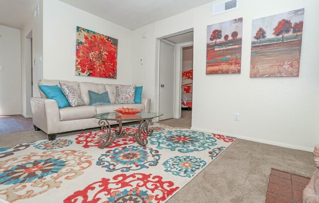 Model living room with a couch, rug and two paintings on the wall at Laurel Parc apartments in Shreveport, LA.