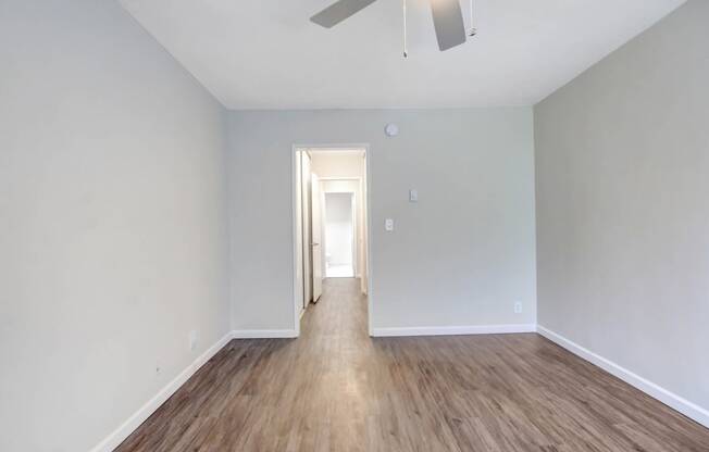 an empty living room with wood floors and a ceiling fan