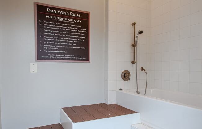 a bathroom with a bathtub and a sign on the wall that says dog wash rules