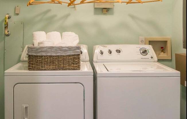 The laundry closet at our apartments in Nashville, featuring a washer and dryer and white racks for storage.