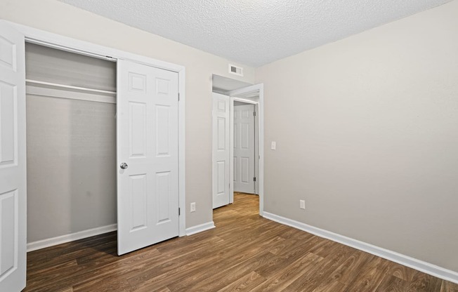 a bedroom with a door to a closet and a hard wood floor