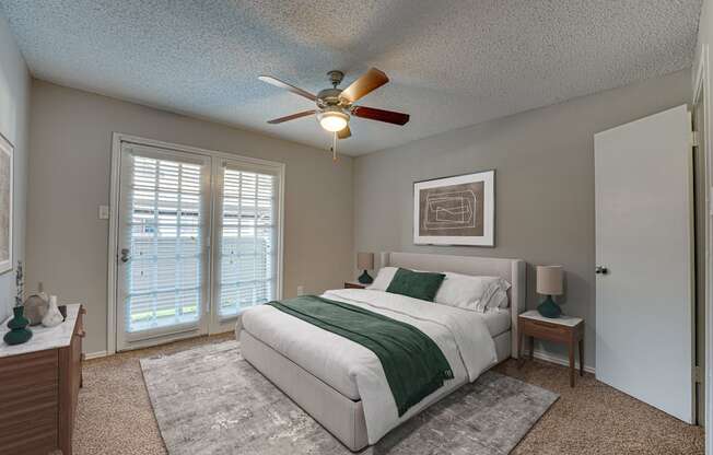 A bedroom with a bed, nightstand, and a ceiling fan.