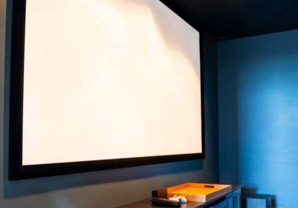 a projector screen in a blue room with a wooden table