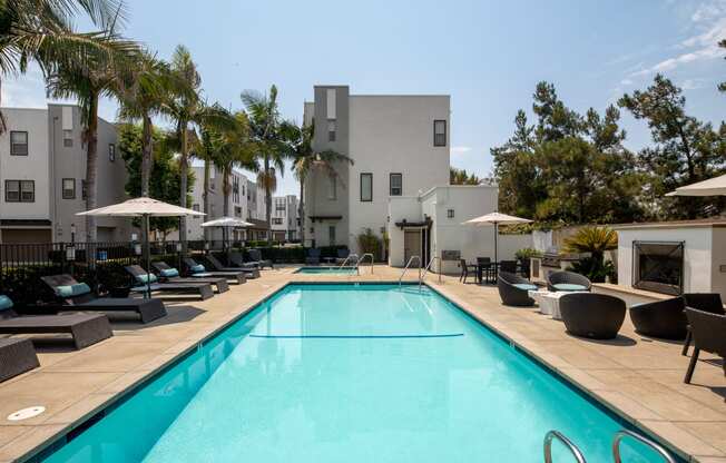 A swimming pool surrounded by lounge chairs and umbrellas.