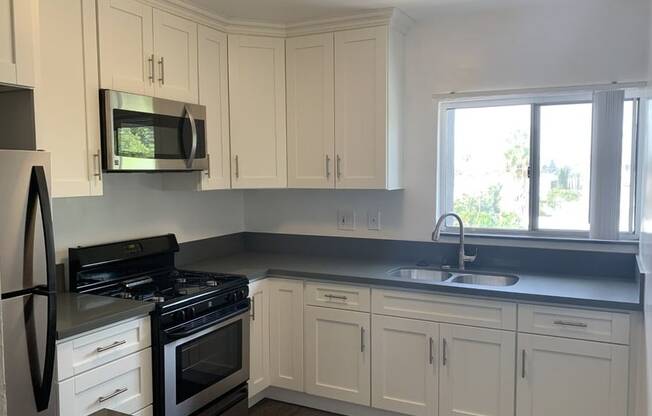 A kitchen with white cabinets and a black stove top oven.