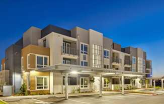 a modern apartment building with a parking lot at night