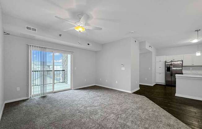 an empty living room with a ceiling fan and a window