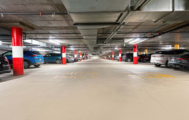 a parking garage with cars and red and white pillars