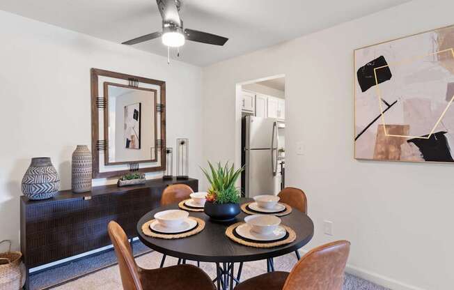 A dining room with a table set for two and a ceiling fan.