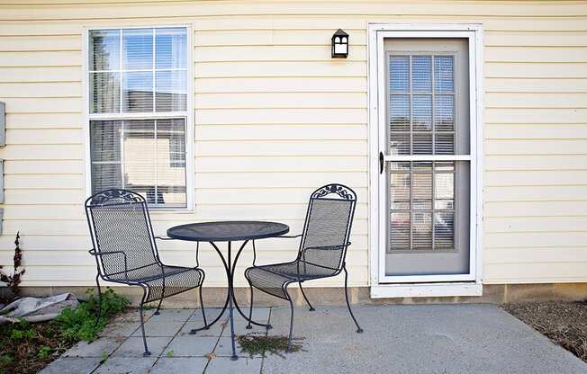 a patio with a table and chairs in front of a house