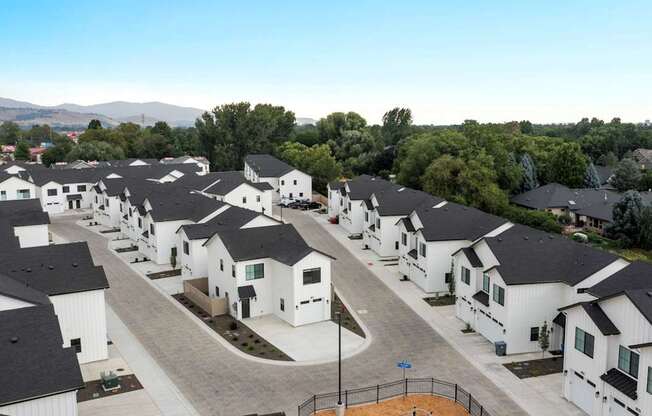 A row of white houses with black roofs are lined up in a residential area.
