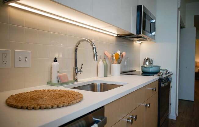 A kitchen with a white counter top and a stainless steel faucet.