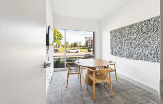 A room with a table and chairs and a painting on the wall.