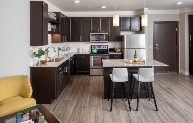 A modern kitchen with dark brown cabinets and a yellow chair.